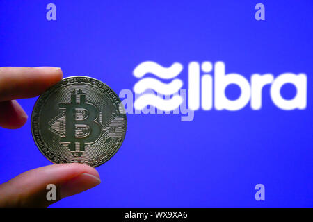 BANGKOK, THAILAND - AUGUST 20, 2019: Bitcoin is holding on hand wth a permissioned blockchain digital currency proposed by Facebook. isolated on blue Stock Photo