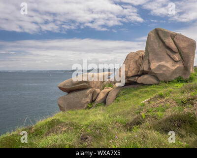 Giant pink boulders on a grassy meadow above the sea along Brittany’s Pink Granit Coast, the Côte de granit rose, near Ploumanach, France. Stock Photo