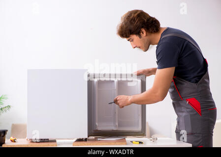 Young handsome contractor repairing fridge Stock Photo
