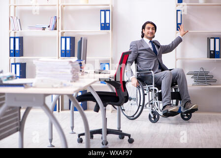 Young handsome employee in wheelchair working in the office Stock Photo