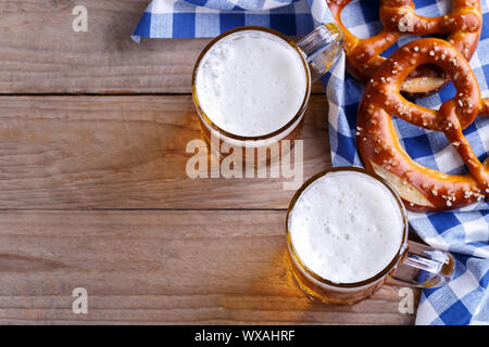 Two pints of beer and pretzels on a blue table cloth, Octoberfest snack Stock Photo