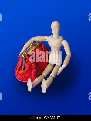 Wooden toy figure with red purse on blue Stock Photo