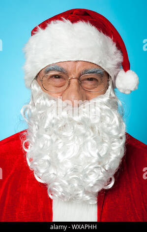 Snapshot of smiling senior man in Santa attire. Isolated on blue background. Stock Photo