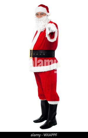 Senior man in Santa costume pointing at you. Isolated against white background. Stock Photo