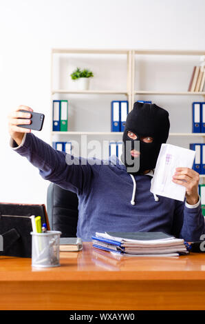 Male thief in balaclava in the office Stock Photo