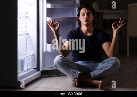 Man breaking diet at night near fridge Stock Photo