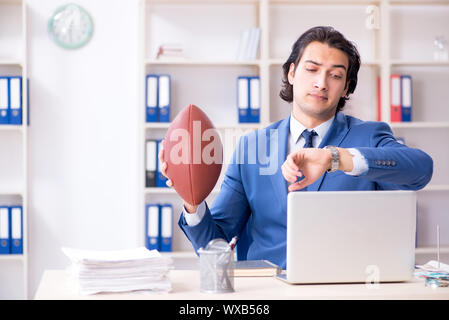 Young handsome businessman with rugby ball in the office Stock Photo