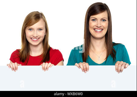 Cheerful young product promoters holding blank white billboard. Stock Photo