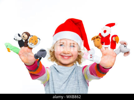 Cute and happy girl in Santa's hat playing with finger puppets, isolated on white. Focus on the finger puppets. Stock Photo