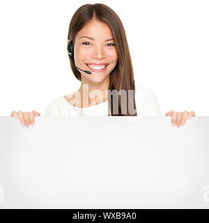 Beautiful Asian woman with a lovely smile wearing a headset and microphone holding a blank white sign in her hands for your advertising or text isolat Stock Photo