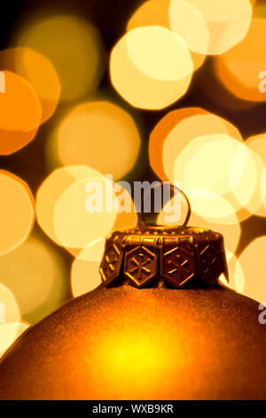 Golden Christmas bauble with blured lights in background, very shallow DOF Stock Photo