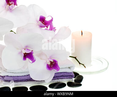 Spa set with white orchid, towels, stones and burning candle on white background Stock Photo