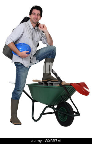 Tradesman with his foot propped up on a wheelbarrow Stock Photo