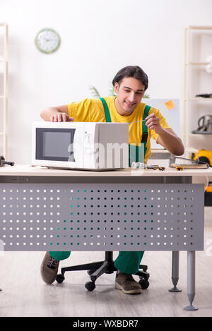 Young repairman repairing microwave in service centre Stock Photo