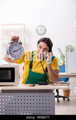 Young repairman repairing microwave in service centre Stock Photo