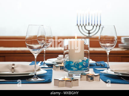 Dinner table setting decorated for Hanukkah. Traditional Jewish holidays home celebrations decor. Stock Photo