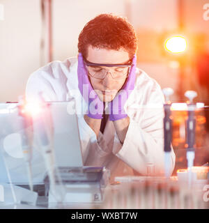 Burned up young post doc PhD researcher sleeping in the laboratory while doing overtime experiments late at night. Stock Photo