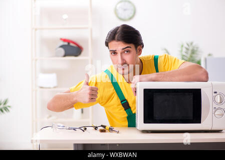 Young repairman repairing microwave in service centre Stock Photo