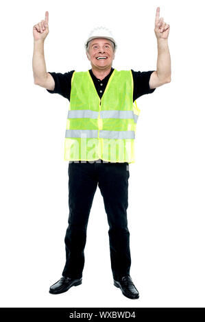 Experienced construction employee pointing his fingers upwards. Full length studio shot. Stock Photo