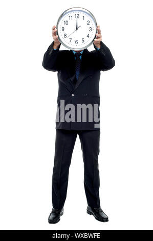 Executive holding up wall clock in front of his face. Clock striking 12. Stock Photo