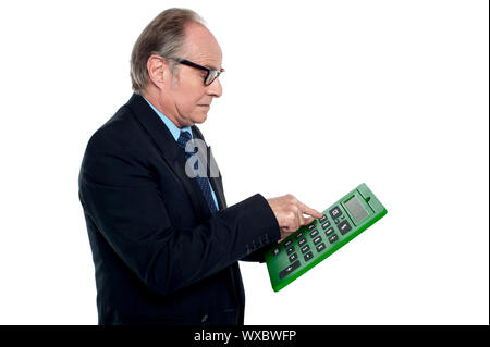 Intent looking executive working on a calculator, pressing digit 7. Stock Photo