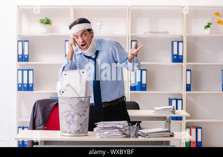 Young injured male employee working in the office Stock Photo