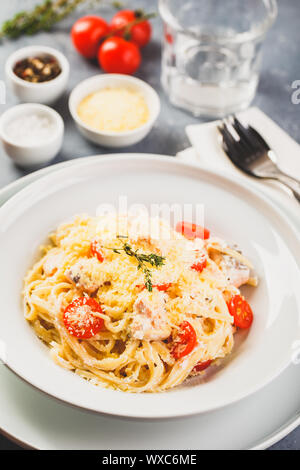 Delicious salmon linguine pasta dish with herbs and grilled salmon filet. Stock Photo
