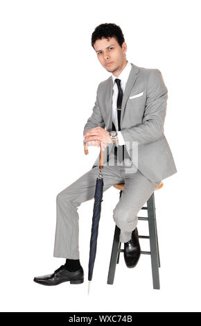 Young bossiness man sitting in a gray suit Stock Photo