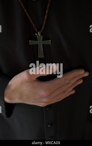 Priest hand below crucifix on black robe Stock Photo