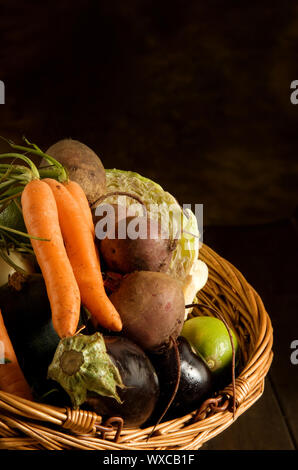 Thanksgiving basket filled with autumn fruits and vegetables on table with mottled background. Stock Photo