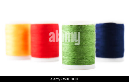 Four spools with green, yellow, blue and red thread Stock Photo