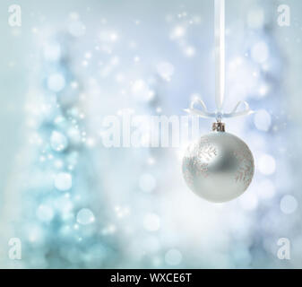Silver Christmas Ornament over glowing tree background Stock Photo