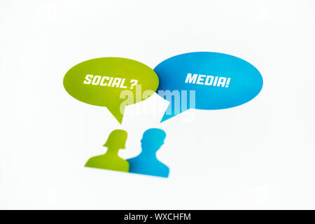 Two figures with speech bubbles and words 'Social' and 'Media' printed on paper. Isolated on white. Stock Photo