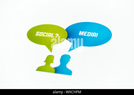 Two figures with speech bubbles and words "Social" and "Media" printed on paper. Isolated on white. Stock Photo