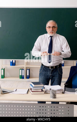 Senior teacher with books and chalkboard. Old smiling professor on ...