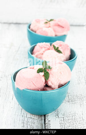 Three bowls of strawberry or raspberry sorbet in a row, garnished with fresh mint. Stock Photo