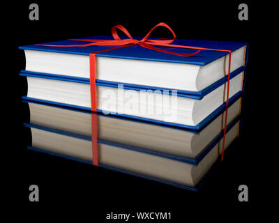 Two blue books with red silk ribbon, isolated on black background. Stock Photo