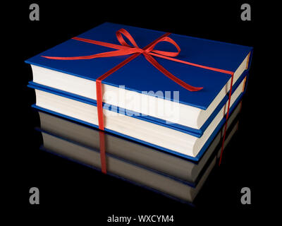 Two blue books with red silk ribbon, isolated on black background. Stock Photo