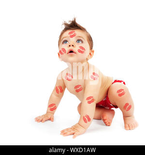 Photo of lovely baby boy try to get up, portrait of cute child isolated on white background, little adorable kid covered red lipstick kisses, nice Cup Stock Photo