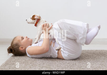 Children, pets and animal concept - Child girl play with her Jack Russell Terrier puppy indoors Stock Photo