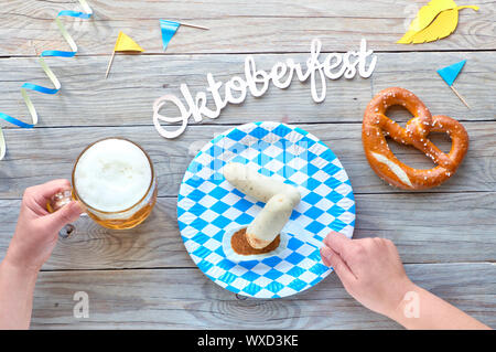 Oktoberfest, traditional festival food: white sausages, pretzel and beer. flat lay on rustic wooden table with blue and white checkered decorations an Stock Photo