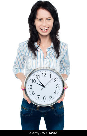 Gorgeous young female displaying round shaped wall clock to the camera. Stock Photo