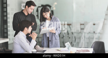 Young female businesswoman explaining her strategy to team members while using tablet Stock Photo