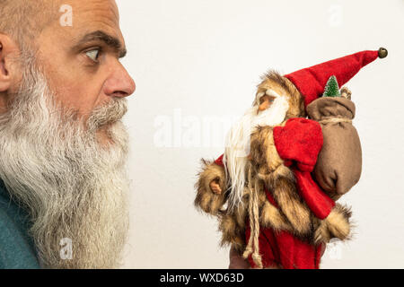 bearded man looking to a Santa Claus puppet Stock Photo