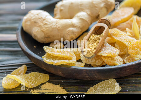 Ginger root and candied ginger on a wooden plate. Stock Photo