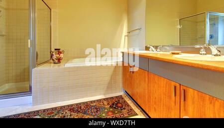 Bathroom with modern wood cabinets, tub and shower with yellow walls. Stock Photo