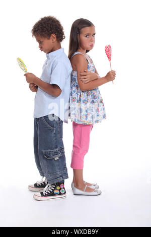 a little boy and a little girl pouting and eating ice cream Stock Photo