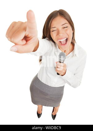 Fun high angle view of a passionate attractive young woman holding a microphone singing or making a point during a speech gesturing and pointing her f Stock Photo