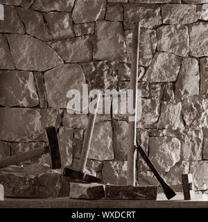 Hammer mason tools of stonecutter masonry work in a contruction stone wall Stock Photo