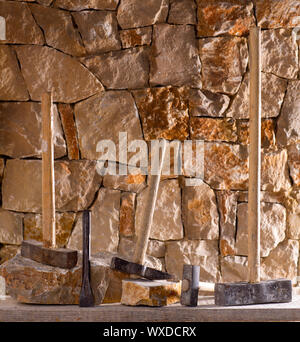 Hammer mason tools of stonecutter masonry work in a contruction stone wall Stock Photo